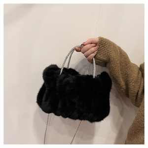 Détail d'un sac nuage en fausse fourrure noire avec poignées en strass et bandoulière