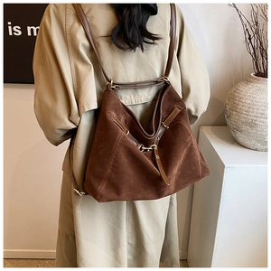 Detail of vintage brown suede multi-way backpack with leather straps and metal buckles