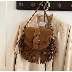Close-up of vintage brown saddle bag with long tassels and golden horseshoe buckle detail