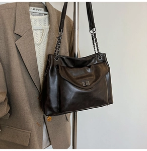 Dettaglio della borsa tote in pelle marrone scuro con tracolla a catena e tasca frontale
