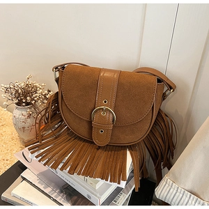 Macro detail of brown suede saddle bag with fringe tassels and vintage metal buckle