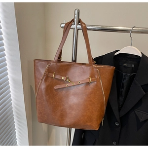 Detail view of brown tote bag with vintage metal zippers and leather straps on blazer