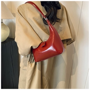 Dettaglio di una borsa a spalla in pelle verniciata rossa lucida indossata da una modella