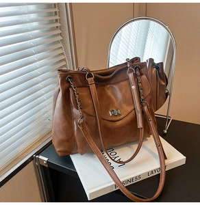 Dettaglio borsa tote in pelle caramello con chiusura a scatto e doppia tracolla a catena