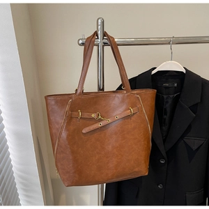Detail of vintage brown PU leather tote with zipper and metal buckle decorative straps