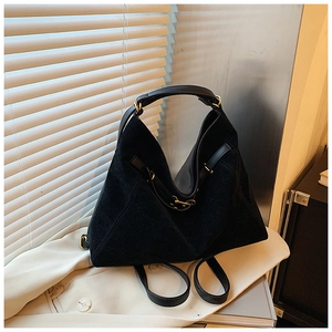 Detailed side view of black suede tote bag showing geometric triangle structure and gold buckle