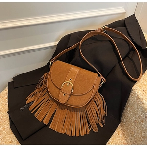 Close-up of brown fringe saddle bag with golden buckle and matte suede finish details