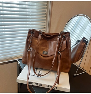 Dettaglio di una borsa tote in pelle PU marrone con chiusura in metallo argento e catena