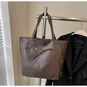 Detailed macro view of dark brown retro tote bag with gold zippers and faux leather texture