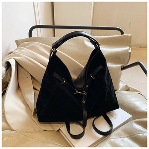 Detail of matte black suede texture with glossy leather straps and gold metal hardware