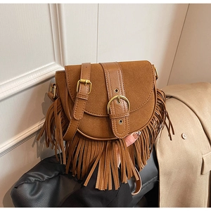 Detail of vintage brown suede saddle bag featuring long fringe tassels and golden buckle