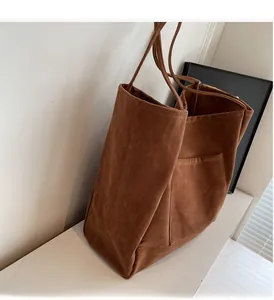 Close-up of caramel suede tote bag featuring smooth texture and front pocket detail