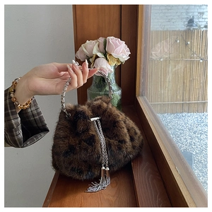 Detail der Leoparden-Plüschtasche mit silbernem Metallgriff und Fransen auf Holzleiste