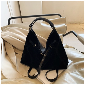 Macro detail of black matte hobo bag with gold hardware on a cream leather chair
