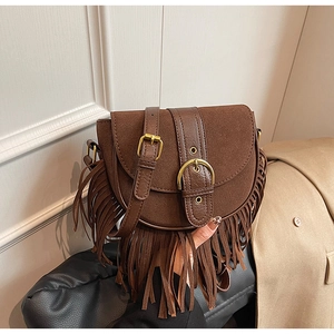 Close-up of vintage brown suede saddle bag featuring long tassels and gold metal buckle