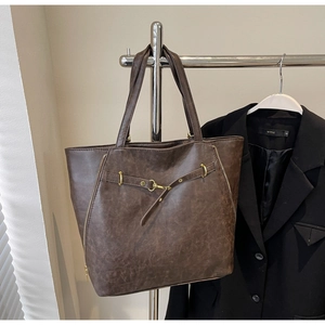 Detailed view of deep brown vintage leather tote with decorative zippers and bronze hardware
