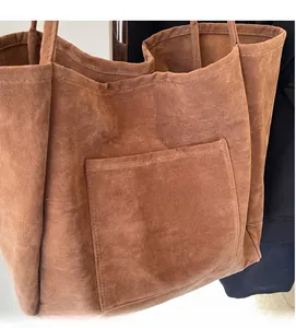 Close-up of brown suede tote bag showing soft fabric texture and front pocket detail