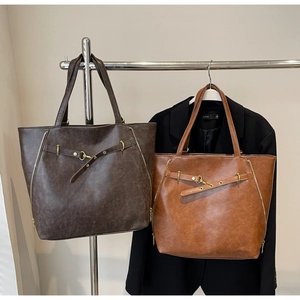 Close-up of retro PU leather tote bags in dark brown and caramel with golden metal buckles