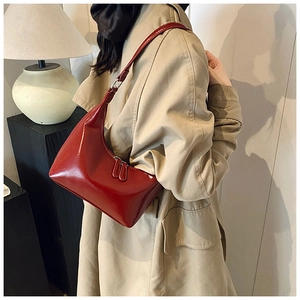 Elegante borsa hobo rossa lucida indossata da una modella con un classico trench beige