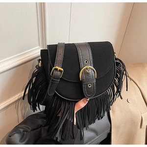 Close-up of bohemian black fringe saddle bag featuring matte suede and gold metal buckles