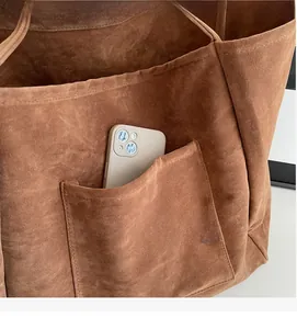 Macro shot of the brown faux suede tote bag inner pocket with a smartphone inside