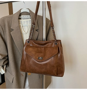Dettaglio borsa tote marrone scuro con texture opaca, chiusura a scatto argento e catena