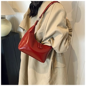 Vista laterale di una borsa hobo in vernice rossa indossata da una modella in trench