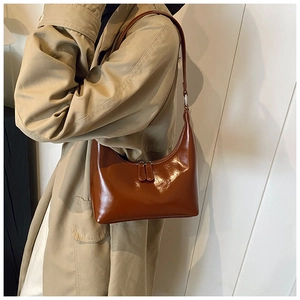 Dettaglio della pelle oliata marrone scuro liscia su una borsa a tracolla minimalista