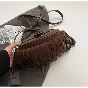 Detail shot of brown suede fringe shoulder bag with adjustable strap and leather trim