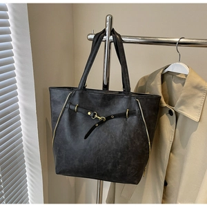 Close-up of black retro tote bag with golden lock and zipper detail on display