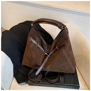Detailed close-up of dark brown suede tote bag featuring leather straps and vintage hardware