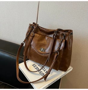 Dettaglio della borsa tote in pelle marrone con chiusura a scatto e tracolla a catena