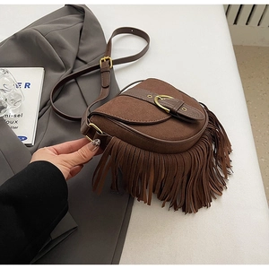 Close-up of vintage saddle bag with brown suede texture and decorative fringe tassels
