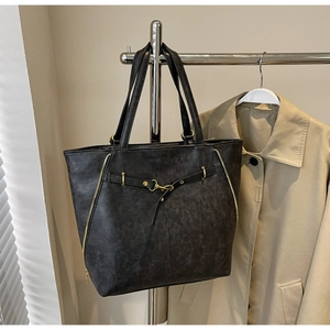 Detail of vintage grey PU leather tote bag with gold decorative zippers on metal display stand