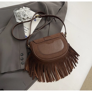 Close-up of vintage brown saddle bag featuring layered tassels and matte leather texture