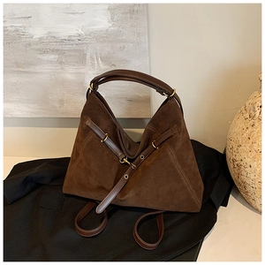 Detailed shot of dark brown vintage suede bag with gold hardware on black fabric