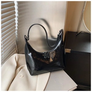 Elegante borsa a spalla a mezza luna nera in finta pelle lucida su un blazer beige