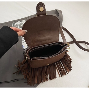 Detail view of the brown saddle bag showing interior zipper and suede fringe texture