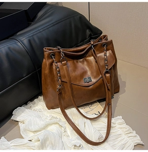 Dettaglio della borsa tote marrone con chiusura girevole in metallo e tracolla a catena