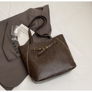 Detail of vintage brown tote bag with decorative zippers and metallic buckle design