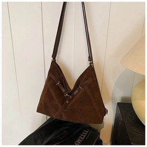 Detail of dark brown suede tote bag with cross straps and gold hardware on white background