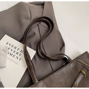 Detail view of large brown leather tote bag with metallic zipper and shoulder strap