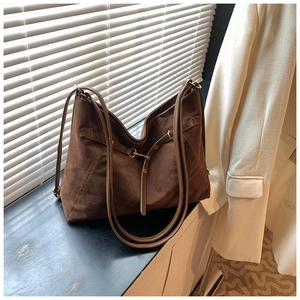 Detailed macro view of the dark brown suede texture and golden metal buckle on tote bag
