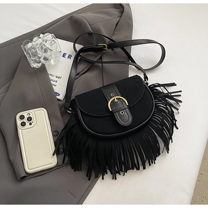Detail of black fringe crossbody bag featuring a golden buckle and matte leather texture