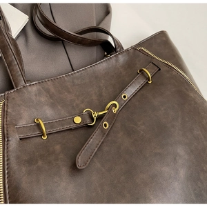 Detailed macro view of vintage brown leather tote bag with elegant gold metal hardware