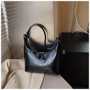 Dettaglio di una borsa hobo in pelle lucida nera con cerniere in argento lucido