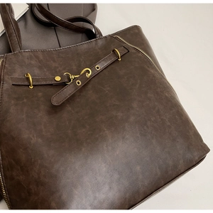 Detail of dark brown vintage tote bag with bronze hardware and textured faux leather