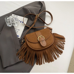 Detail of vintage brown saddle bag with long tassels and golden metallic buckle