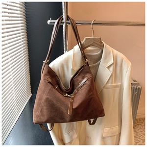 Detail of vintage brown suede tote bag featuring smooth leather straps and gold hardware