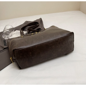 Detail of vintage dark brown faux leather tote bag with smooth zipper and metal hardware
